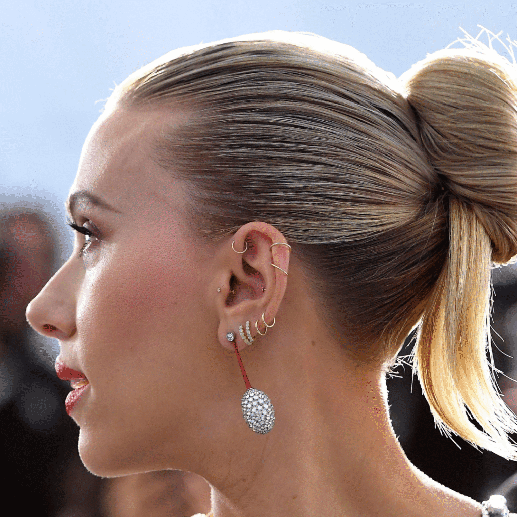 Scarlett Johansson with multiple lobe, helix, and conch piercings styled with gold studs