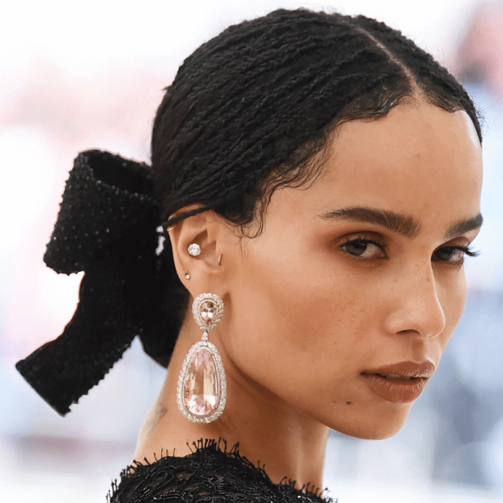 Zoë Kravitz with dainty forward helix and tragus piercings in a minimalist gold style