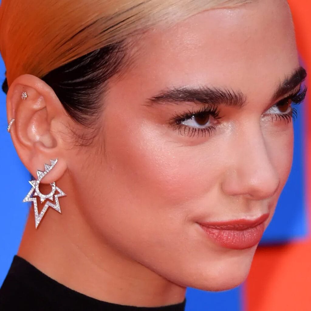 Dua Lipa ear piercings styled with elegant jewelry on red carpet