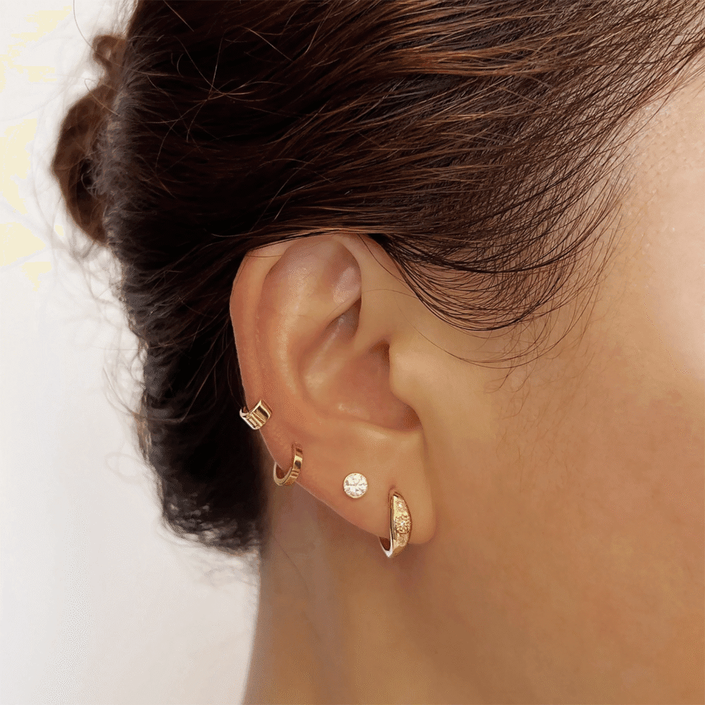 Combination of dainty gold hoops and diamond studs creating a refined ear stack