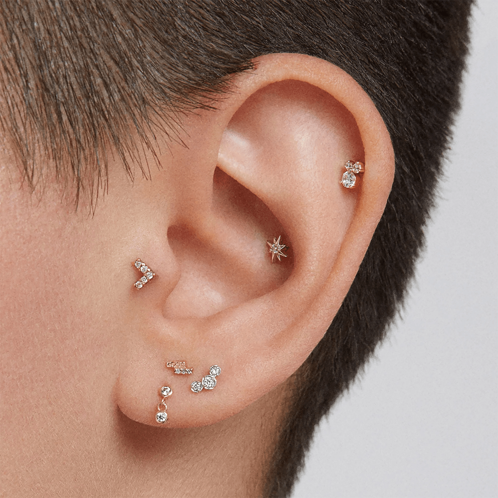 Simple cartilage piercing stack with matching gold jewelry on upper ear