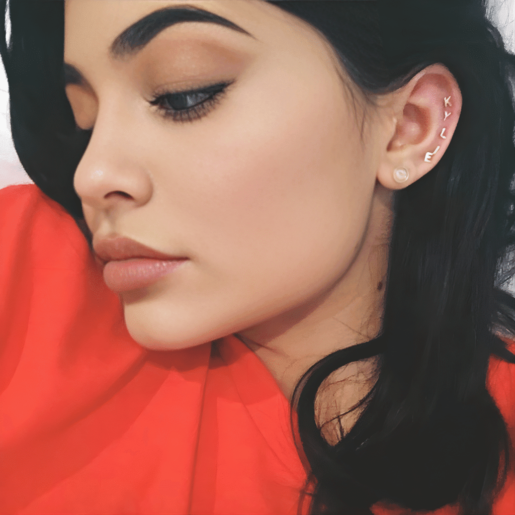 Kylie Jenner curated ear stack with multiple gold earrings and soft glam makeup