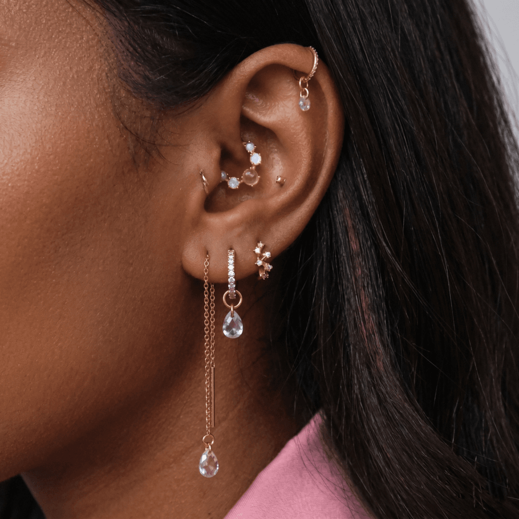 A collection of minimalist 14K gold studs including stars and tiny balls designed for flat constellation ear curation.
