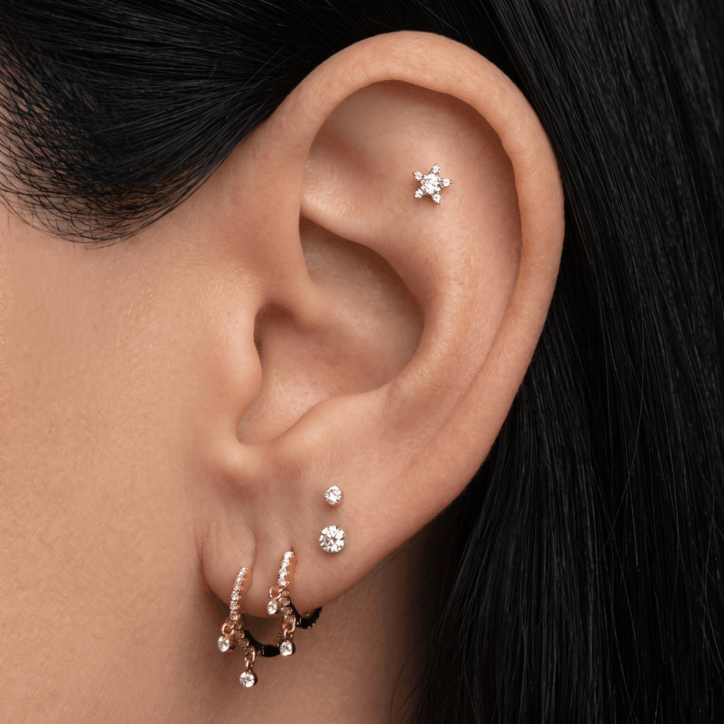 A close up of a minimalist 14K gold star stud ideal for styling a tash rook piercing.