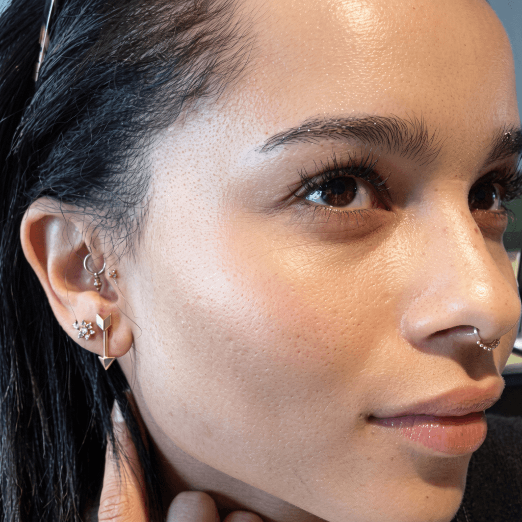 Gold hoops, cartilage jewelry, and delicate chains reflecting the ear piercing style of Zoë Kravitz
