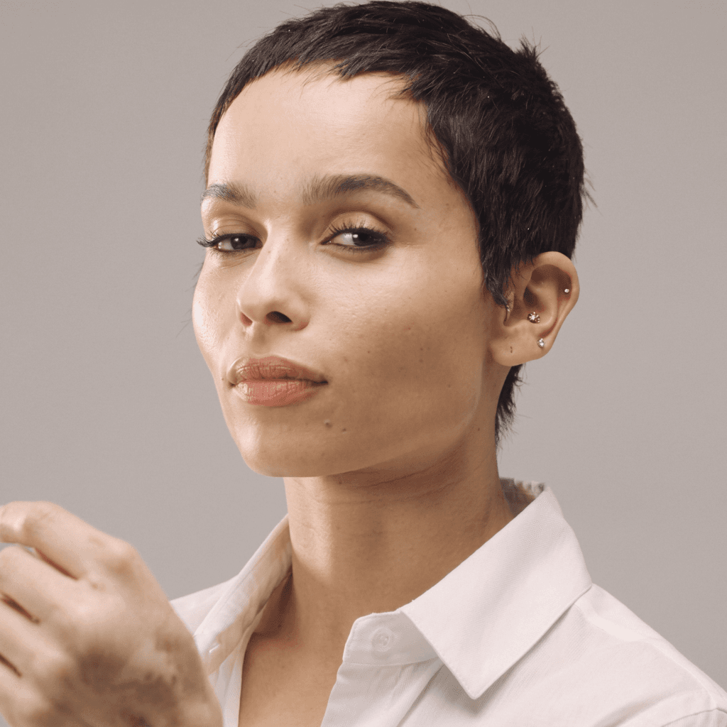 Inner ear hoop and multiple lobe studs create a layered piercing look often associated with Zoë Kravitz style